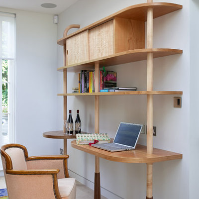 Trendy built-in desk beige floor study room photo in London with white walls
