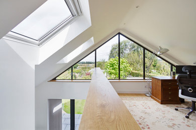 This is an example of a medium sized modern study in West Midlands with white walls, laminate floors, a freestanding desk, beige floors and a vaulted ceiling.