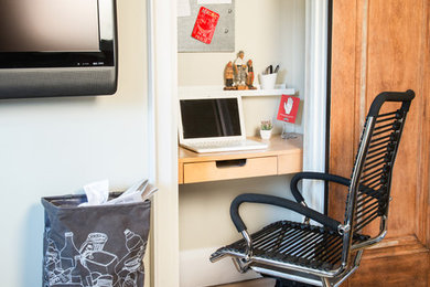 Ejemplo de despacho de estilo americano pequeño sin chimenea con paredes blancas, suelo de madera clara, escritorio empotrado y suelo marrón
