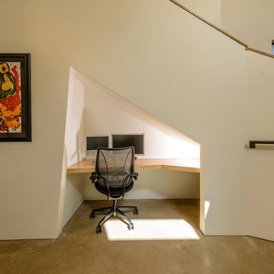 Small trendy built-in desk concrete floor study room photo in Austin with white walls and no fireplace
