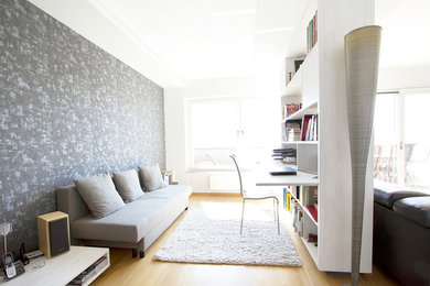 Ejemplo de despacho minimalista sin chimenea con escritorio empotrado, paredes grises, suelo de madera clara y suelo marrón