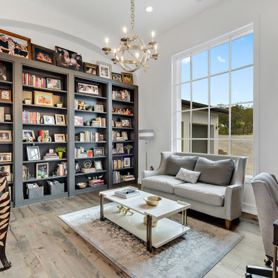 Large tuscan freestanding desk medium tone wood floor and brown floor study room photo in Austin with white walls