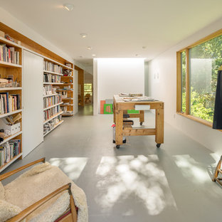 Mittelgroßes Modernes Arbeitszimmer mit Studio, weißer Wandfarbe, Kaminofen, Kaminumrandung aus Metall, freistehendem Schreibtisch, grauem Boden und Betonboden in Boston