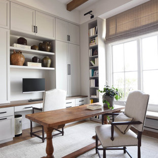 Klassisches Arbeitszimmer mit weißer Wandfarbe, dunklem Holzboden, freistehendem Schreibtisch, braunem Boden und freigelegten Dachbalken in Austin