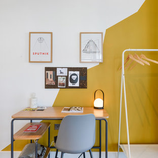 Photo of a small eclectic study in London with white walls, a freestanding desk and brown floors.