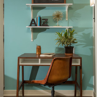 Kleines Klassisches Arbeitszimmer ohne Kamin mit blauer Wandfarbe, Betonboden, freistehendem Schreibtisch und braunem Boden in Detroit
