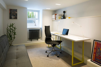 This is an example of a small contemporary study in Sussex with white walls, carpet and a freestanding desk.