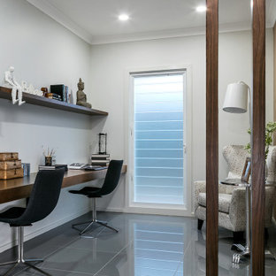 Inspiration for a mid-sized transitional study room in Other with white walls, a built-in desk and grey floor.
