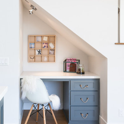 Home office - coastal built-in desk dark wood floor home office idea in Orange County with white walls