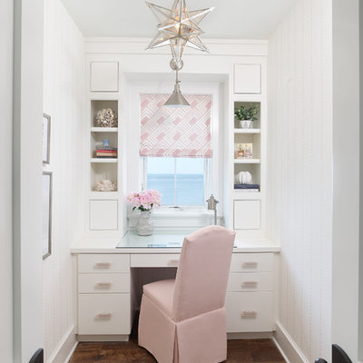 Example of a beach style built-in desk dark wood floor and brown floor home office design in Charleston with white walls