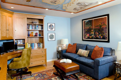 Ejemplo de despacho tradicional con paredes azules, suelo de madera en tonos medios y escritorio empotrado