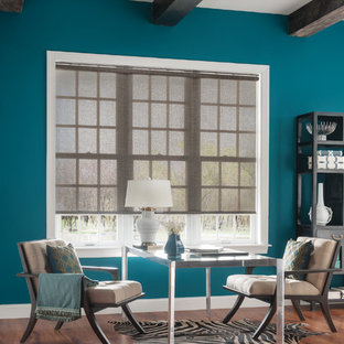 Cette image montre un grand bureau design avec un mur bleu, un sol en bois brun et un bureau indépendant.