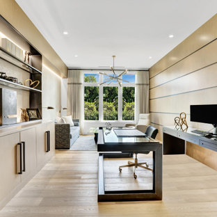 Großes Modernes Arbeitszimmer mit Arbeitsplatz, beiger Wandfarbe, hellem Holzboden, freistehendem Schreibtisch, beigem Boden und Holzwänden in Miami
