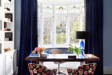 Diseño de despacho ecléctico de tamaño medio con paredes azules, suelo de madera en tonos medios, escritorio independiente y suelo marrón