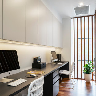 This is an example of a contemporary study room in Sunshine Coast with white walls, medium hardwood floors, no fireplace, a freestanding desk and brown floor.