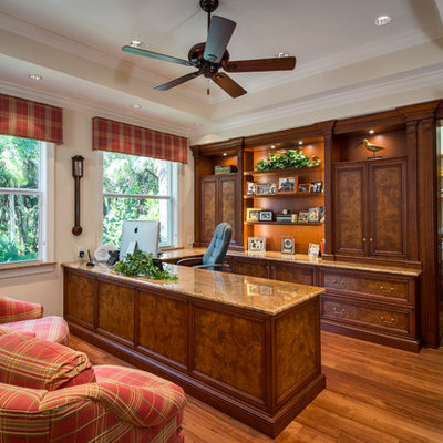 Elegant built-in desk medium tone wood floor study room photo in Miami with beige walls