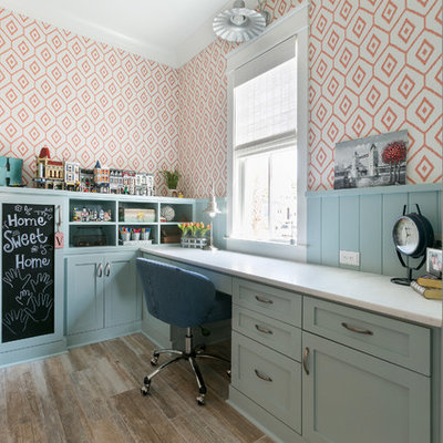 Example of a beach style built-in desk medium tone wood floor and brown floor study room design in Charleston with orange walls and no fireplace