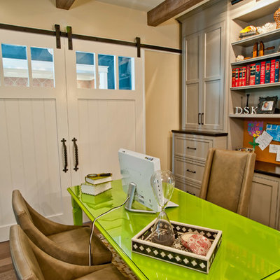 Elegant freestanding desk dark wood floor home office photo in Los Angeles with beige walls
