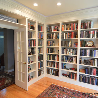 Esempio di uno studio classico di medie dimensioni con libreria, pareti blu, parquet chiaro, camino classico e cornice del camino in pietra
