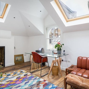 Inspiration for a bohemian home office in London with white walls, medium hardwood flooring, a standard fireplace, a freestanding desk and brown floors.