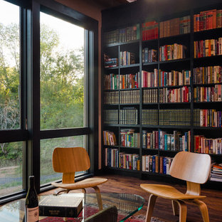 Idéer för ett mellanstort modernt hemmabibliotek, med svarta väggar, mellanmörkt trägolv och ett fristående skrivbord