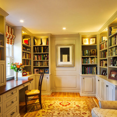 Large elegant built-in desk medium tone wood floor home office photo in New York with white walls