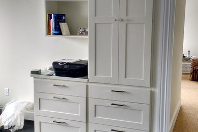 Foto de despacho actual de tamaño medio con paredes blancas, suelo de madera oscura, escritorio empotrado y suelo negro
