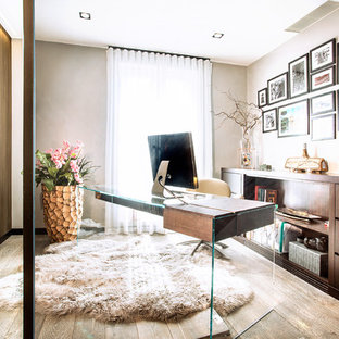 Medium sized contemporary study in London with beige walls, light hardwood flooring, a freestanding desk and beige floors.