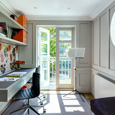 Example of a classic built-in desk light wood floor study room design in London with gray walls