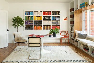 Example of a danish freestanding desk medium tone wood floor and brown floor home office library design in Denver with white walls