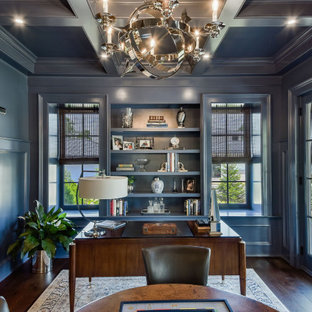 Großes Klassisches Arbeitszimmer ohne Kamin mit Arbeitsplatz, blauer Wandfarbe, dunklem Holzboden, freistehendem Schreibtisch, Kassettendecke und vertäfelten Wänden in Chicago