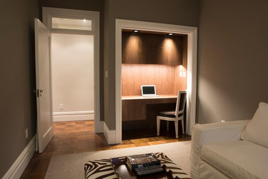 Ejemplo de despacho actual pequeño sin chimenea con escritorio empotrado, paredes grises, suelo de madera en tonos medios y suelo marrón
