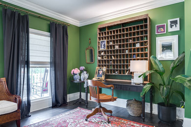 Ejemplo de despacho tropical grande sin chimenea con paredes verdes, suelo de madera oscura, escritorio independiente y suelo negro
