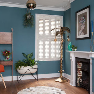 Inspiration for a medium sized bohemian study in London with blue walls, brown floors, dark hardwood flooring, a standard fireplace and a freestanding desk.