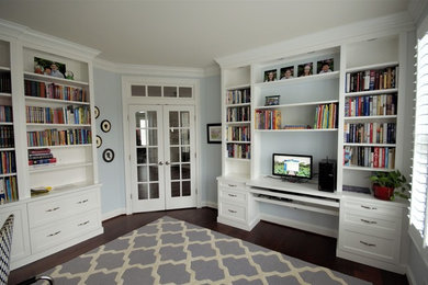 Large transitional built-in desk medium tone wood floor and brown floor study room photo in DC Metro with blue walls and no fireplace