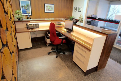 На фото: рабочее место в современном стиле с белыми стенами, бетонным полом и встроенным рабочим столом без камина с