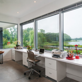 Cette photo montre un grand bureau moderne de type studio avec un mur blanc, béton au sol, un bureau indépendant et un sol gris.