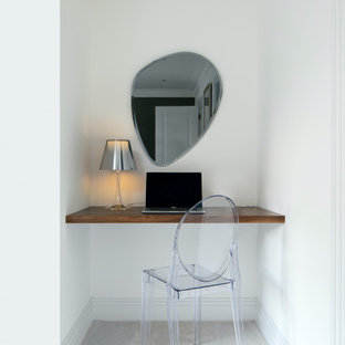 This is an example of a small contemporary study in Essex with white walls, carpet, a built-in desk and grey floors.