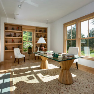 Mittelgroßes Modernes Arbeitszimmer mit Kaminumrandung aus Beton, Arbeitsplatz, weißer Wandfarbe, hellem Holzboden, Kamin und freistehendem Schreibtisch in New York
