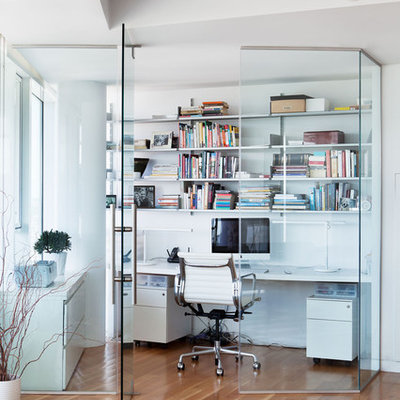 Trendy built-in desk medium tone wood floor home office photo in New York with white walls
