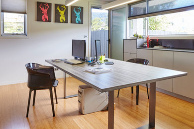 Foto de estudio moderno con paredes grises, suelo de bambú y escritorio independiente
