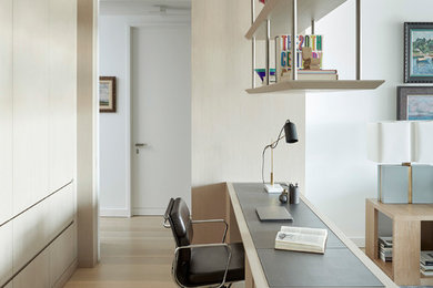 Example of a trendy built-in desk light wood floor and beige floor home office design in New York with white walls
