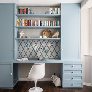 Inspiration för mellanstora klassiska hemmabibliotek, med beige väggar, mörkt trägolv, ett inbyggt skrivbord och brunt golv