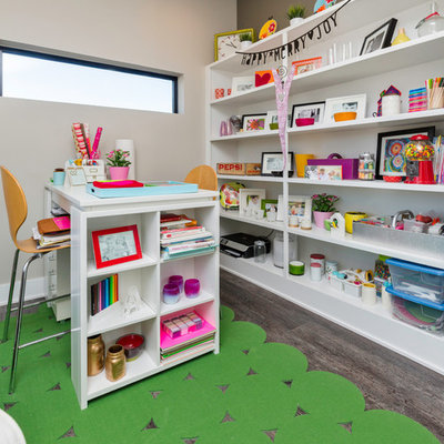 Craft room - mid-sized contemporary built-in desk medium tone wood floor craft room idea in Other with brown walls and no fireplace