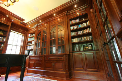 Immagine di uno studio chic di medie dimensioni con libreria, pareti marroni, pavimento in bambù, nessun camino e scrivania incassata