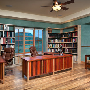 Large tuscan freestanding desk medium tone wood floor home office photo in Denver with blue walls