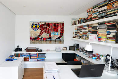 Ejemplo de despacho bohemio de tamaño medio sin chimenea con suelo de madera clara, escritorio empotrado y paredes blancas