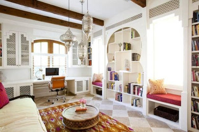 他の地域にある中くらいなトランジショナルスタイルのおしゃれなホームオフィス・書斎 (白い壁、ライムストーンの床、暖炉なし、造り付け机、ベージュの床) の写真