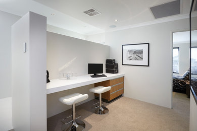 На фото: кабинет в современном стиле с белыми стенами, ковровым покрытием и встроенным рабочим столом без камина с