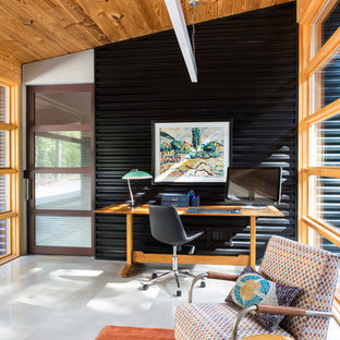 This is an example of a mid-sized country study room in Baltimore with black walls, no fireplace, a freestanding desk, concrete floors and grey floor.